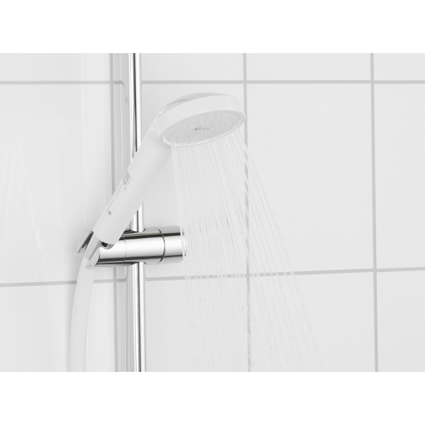 Handdouche met geïntegreerd legionellafilter op chromen glijstang, stromend water tegen witte tegelwand